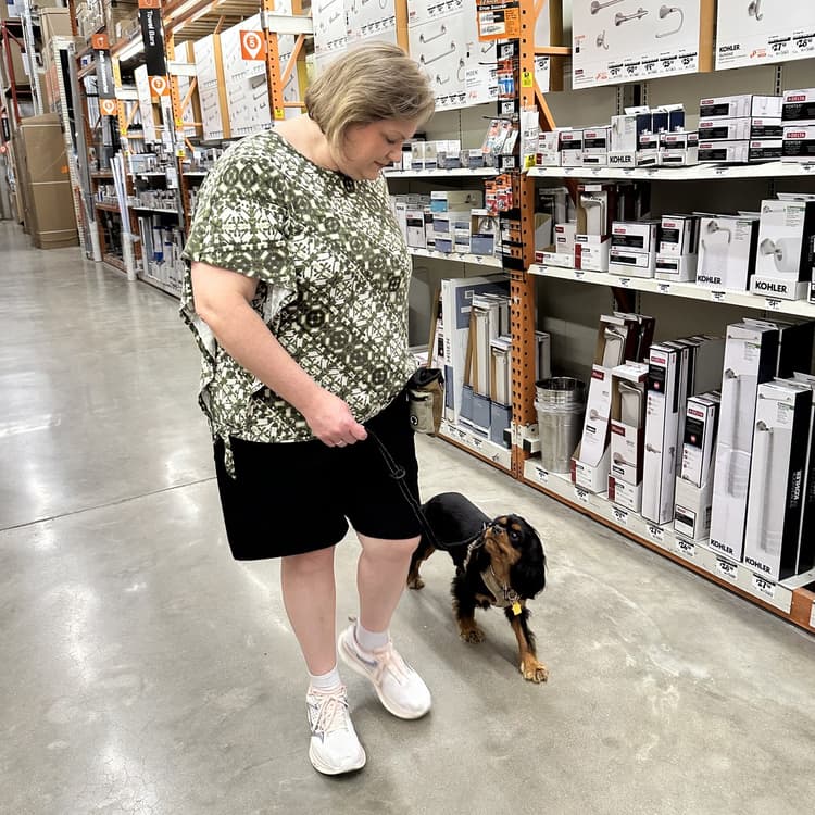 An owner walking her spaniel on a completely slack leash down a busy hardware store aisle