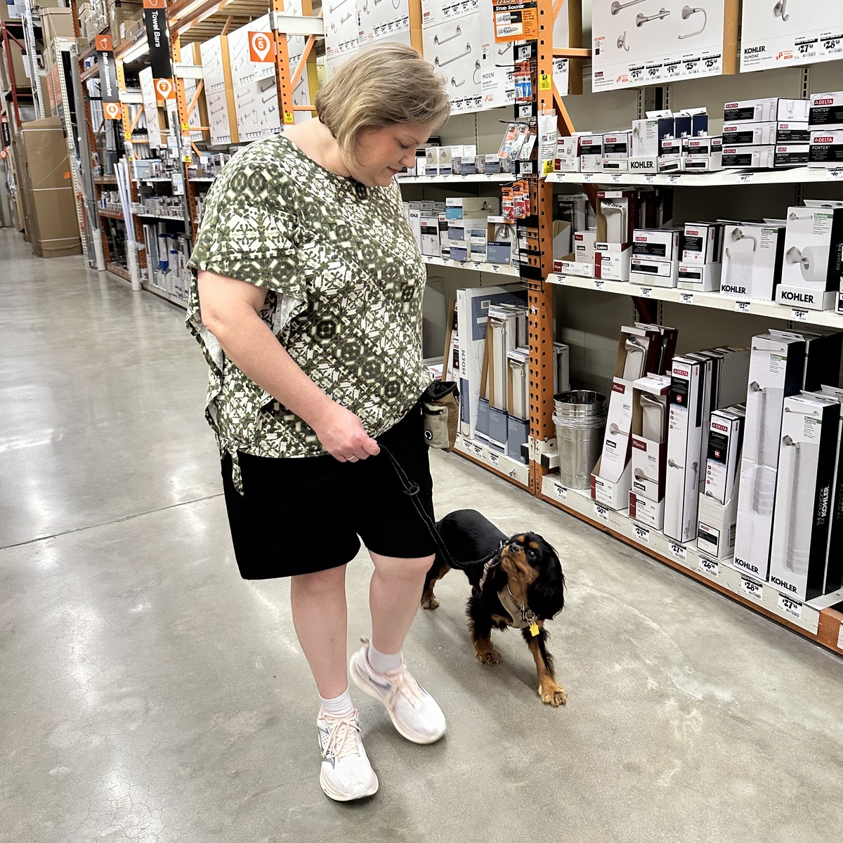 An owner walking her spaniel on a completely slack leash down a busy hardware store aisle